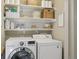 A bright laundry room with white washer and dryer and shelving for ample storage space at 10570 Humboldt Peak Way, Parker, CO 80138