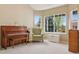 Sunlit living room featuring a piano, wingback chair, and large windows with serene outdoor views at 10570 Humboldt Peak Way, Parker, CO 80138