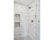 Luxurious shower with white marble tile, mosaic niches, and modern fixtures at 10570 Humboldt Peak Way, Parker, CO 80138