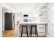 Bright kitchen with white cabinets, stainless steel appliances, hardwood floors, and a sleek island with seating at 7060 S Windsor St, Littleton, CO 80128