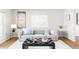 Comfortable living room with a gray sofa, patterned ottoman, hardwood floors, and ample natural light from the window at 7060 S Windsor St, Littleton, CO 80128