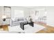 Bright living room with hardwood floors, modern furnishings, and an open layout leading to the dining area at 7060 S Windsor St, Littleton, CO 80128