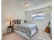 Comfortable bedroom with a patterned bedspread, side table with lamp, and window at 9057 E Oxford Dr, Denver, CO 80237
