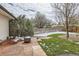 Backyard featuring a stone patio, green grass, mature trees, and privacy fence in winter at 2221 S Arbutus Ct, Lakewood, CO 80228