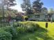 Green backyard with mature trees and vibrant flower beds at 1392 S Edison Way, Denver, CO 80222