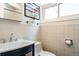 Well-lit bathroom featuring a vanity with chrome fixtures, toilet, and tiled walls below a sunny window at 1392 S Edison Way, Denver, CO 80222