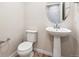 Well-lit half bathroom featuring modern fixtures, a pedestal sink, and a round mirror at 19058 E 94Th Pl, Commerce City, CO 80022