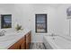 Well-lit bathroom boasts dual sinks, modern tub, and a large window at 10157 W Fremont Pl, Littleton, CO 80127
