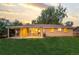 Brick house with a covered patio and spacious backyard with mature trees at dusk at 2391 S Quitman St, Denver, CO 80219