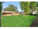 Large backyard with mature trees, green grass and partial views of the brick house at 2391 S Quitman St, Denver, CO 80219