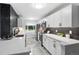 Modern kitchen featuring white cabinets, quartz countertops, stainless steel appliances, and stylish black backsplash at 2391 S Quitman St, Denver, CO 80219
