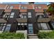 Modern townhome featuring a mix of wood and black metal siding, private balconies, and bright blue doors at 1534 Irving St, Denver, CO 80204