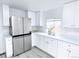 Spacious kitchen showcasing stainless steel refrigerator and modern white cabinets at 815 Plum Ave, Lochbuie, CO 80603