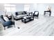 Bright living room with grey sofa, black tables, decorative pillows, and light wood-look flooring at 815 Plum Ave, Lochbuie, CO 80603
