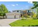 Inviting two-story home with a three-car garage, brick accents, and a green lawn at 8806 Tuscany Ln, Highlands Ranch, CO 80130