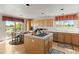 Well-lit kitchen with natural wood cabinets, cooktop island, and breakfast nook overlooking lush greenery at 8806 Tuscany Ln, Highlands Ranch, CO 80130