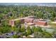 Aerial shot of a multi-building brick school house surrounded by lush green trees in a residential neighborhood at 2300 Jasmine St, Denver, CO 80207