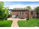 Expansive brick home backyard featuring a charming pergola-covered patio, lush lawn, and manicured landscaping at 2300 Jasmine St, Denver, CO 80207