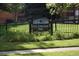 A view of a park sign with wrought iron fencing, a grassy field and neighborhood greenery at 2300 Jasmine St, Denver, CO 80207