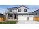 Charming two-story home with a three car garage, gray siding, black shutters, stone accents, and a cozy front porch at 4211 Sandstone Dr, Mead, CO 80504
