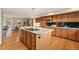 Spacious kitchen featuring wood cabinets, granite counters, and an island with a cooktop at 15846 W Bayaud Dr, Golden, CO 80401