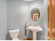 Powder room featuring a pedestal sink, round mirror, and light blue walls at 15846 W Bayaud Dr, Golden, CO 80401