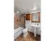 Well-lit bathroom featuring a bathtub/shower combo with glass doors, pedestal sink, and vanity with decorative mirror at 13404 E Jewell Ave # 101, Aurora, CO 80012