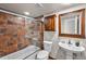 Well-lit bathroom featuring a bathtub/shower combo with glass doors, pedestal sink, and vanity with decorative mirror at 13404 E Jewell Ave # 101, Aurora, CO 80012