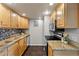 Modern kitchen featuring granite countertops, stainless steel appliances, wooden cabinets, and dark tiled flooring at 13404 E Jewell Ave # 101, Aurora, CO 80012