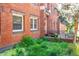 This brick exterior features lush green landscaping, a small deck, and a set of windows looking into the units at 1365 N Corona St # 11, Denver, CO 80218