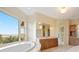 Bathroom featuring a soaking tub, spacious vanity with storage, and a large window overlooking scenic views at 606 Cliffgate Ln, Castle Rock, CO 80108
