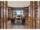Spacious home office with custom built-in bookshelves, hardwood floors, and scenic outdoor view at 606 Cliffgate Ln, Castle Rock, CO 80108