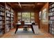Elegant office space with custom wood bookshelves, coffered ceiling, and large window showcasing lush greenery at 606 Cliffgate Ln, Castle Rock, CO 80108