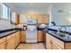 Well-maintained kitchen with light wood cabinetry, black countertops, and white appliances at 85 Uinta Way # 702, Denver, CO 80230