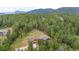Aerial view of a home surrounded by lush mature trees and hills at 14271 Timber Trl, Larkspur, CO 80118