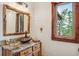 Rustic bathroom with natural wood vanity, copper sink, and views of the surrounding landscape at 14271 Timber Trl, Larkspur, CO 80118