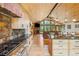 Long view of the kitchen with stainless steel appliances, wooden island, barstool seating, and living space beyond at 14271 Timber Trl, Larkspur, CO 80118