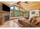 Cozy living room features a stone fireplace, vaulted wood ceilings, and an expansive view of the outdoors at 14271 Timber Trl, Larkspur, CO 80118