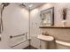 Modern bathroom featuring a pedestal sink, rainfall shower head, and textured tile walls at 8292 E Lehigh Dr, Denver, CO 80237