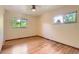A bright, empty bedroom with wood floors, two windows, and a ceiling fan at 8292 E Lehigh Dr, Denver, CO 80237