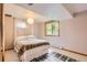 Cozy bedroom with a decorative bedspread, window, overhead light, and patterned rug at 8292 E Lehigh Dr, Denver, CO 80237