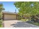 This home features a brick facade, attached two-car garage, and mature trees in a well-maintained front yard at 8292 E Lehigh Dr, Denver, CO 80237