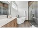Modern bathroom featuring a soaking tub, glass-enclosed shower, and sleek vanity with a marble countertop and contemporary fixtures at 960 Quitman St, Denver, CO 80204