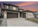 Modern home boasting a three car garage, sleek gray siding, and decorative stone accents against a vibrant sunset sky at 6429 Stable View St, Castle Pines, CO 80108