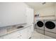 Well-lit laundry room with granite countertop, a sink, cabinets, and modern washer and dryer units at 6429 Stable View St, Castle Pines, CO 80108