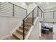 Modern staircase with light wood treads, black metal railing, and a view of the office through a sliding barn door at 6429 Stable View St, Castle Pines, CO 80108