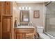 Bright bathroom featuring a modern vanity with granite countertop, decorative mirror, and a shower with glass doors at 148 S Holman Way, Golden, CO 80401