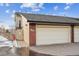 Attached two-car garage with brick accents and a walkway leading to a wooden gate at 148 S Holman Way, Golden, CO 80401