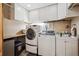 Functional laundry room with white cabinetry, modern washer and dryer, and a utility sink at 148 S Holman Way, Golden, CO 80401