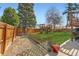 Fenced backyard featuring a play set, mature trees, and manicured lawn at 2034 S Idalia St, Aurora, CO 80013